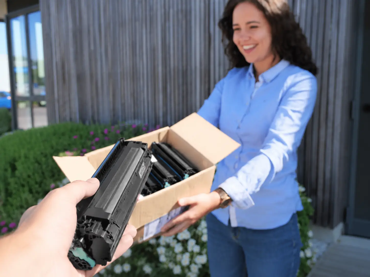 Une personne déposant une cartouche toner vide dans un colis pour son rachat